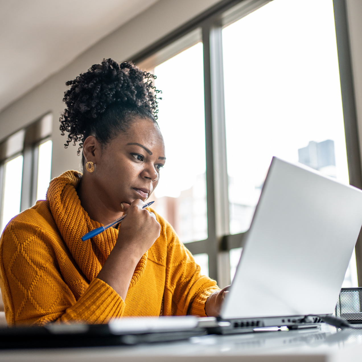 Lady in orange sweater looking at laptop