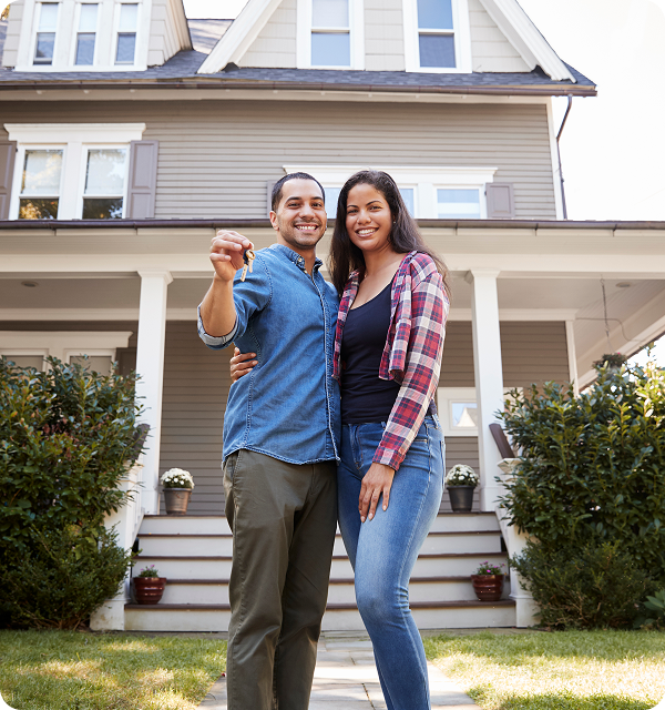 A couple holding keys infront of a new home